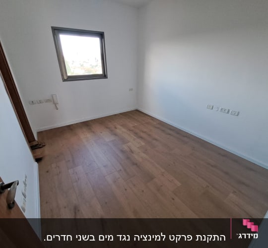 חדר ריק עם רצפת פרקט וחלון.